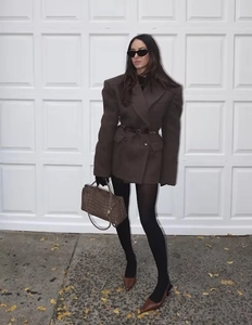 Detail view of brown oversized blazer with padded shoulders and black leather waist belt