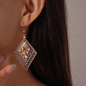 Close-up of bohemian hollow rhombus drop earrings with beads on model ear
