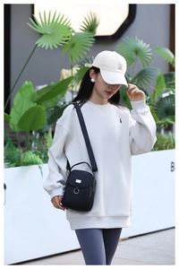 Close-up of lightweight black nylon crossbody bag with adjustable strap on a female model