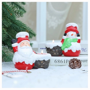 Close-up of Santa Claus and Snowman ceramic candle holders with snow texture and tea lights
