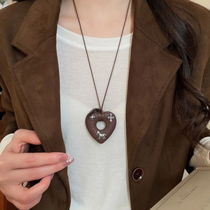 Detailed view of vintage brown heart pendant with silver charms on long cord necklace