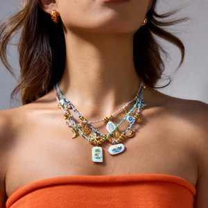 Multilayer gold necklace with colorful charms and earrings shown on a female model