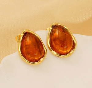 Detail of amber water drop earrings with irregular gold-plated frames on silk
