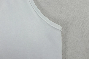 Close-up of neckline stitching on white ruched dress showing high quality tailoring