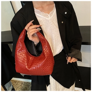 Detail view of woven leather hobo bag in deep red worn with a black tailored blazer