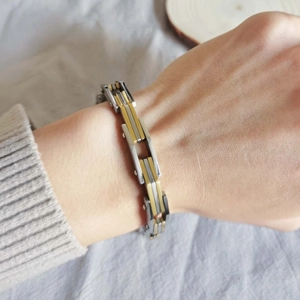 Dettaglio di un bracciale a catena bicolore argento e oro lucido indossato al polso