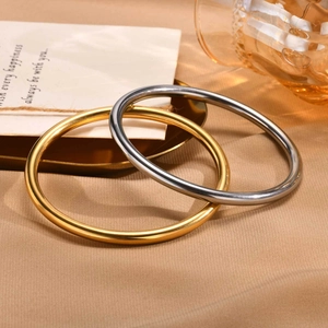 Polished gold and silver stainless steel bangles displayed on a decorative golden tray