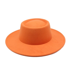 Detail of bright orange wool felt fedora with a wide brim and flat top structure