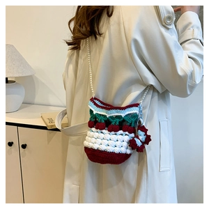 Close-up of handmade crochet cherry bucket bag with white pearl strap and 3D textures