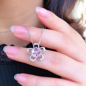 Close-up of cherry blossom pendant with pink gemstones worn by a model on a silver chain