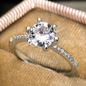 Macro shot of a classic six-prong zircon engagement ring in a beige velvet jewelry box