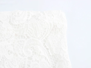 Gros plan détaillé montrant la texture de la dentelle florale et les motifs brodés blancs