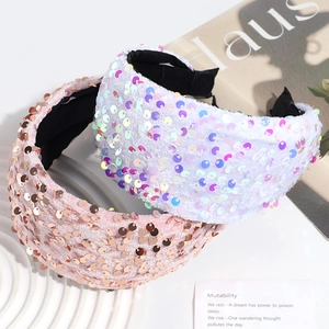 Detail of pink and white sequin wide headbands on a white decorative tray with soft lighting