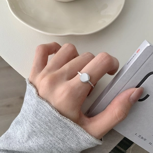 Minimalist S925 sterling silver round ring on model's hand with aesthetic props