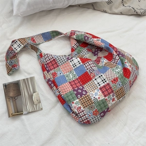 Détail d'un sac à bandoulière vintage en toile patchwork sur un drap blanc plissé