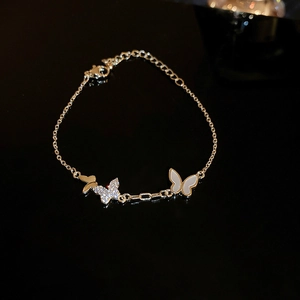 Macro shot of gold butterfly bracelet showing zircon inlay and polished metallic details