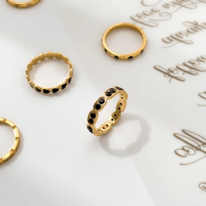 Detail of gold rings with black heart enamel and sparkling black stones on artistic paper