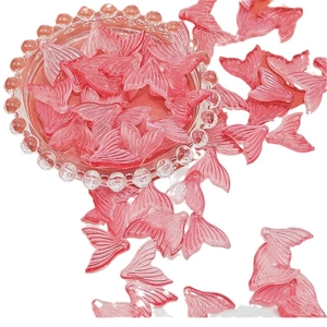 Translucent pink fishtail DIY charms displayed in a decorative glass bowl on white background