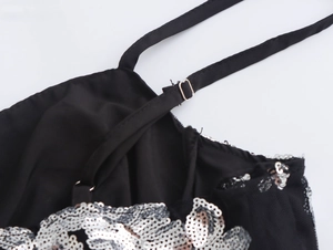 Detail des verstellbaren schwarzen Trägers und der Silberpailletten am eleganten Kleid