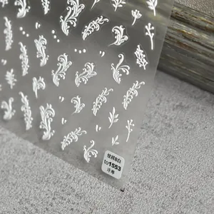 Macro shot of 3D embossed white floral nail art stickers with vintage leaf patterns