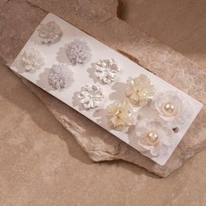 Detailed close-up of a 10-piece acrylic pearl floral earring set on a stone background