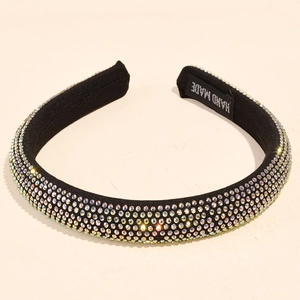 Macro shot of colorful rhinestones on a black padded headband with a Handmade label