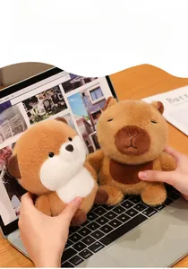 Close-up of soft plush capybara and fox toys being held over a laptop keyboard