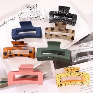 Flat lay of nine large hollow hair claws in diverse colors on a white display tray