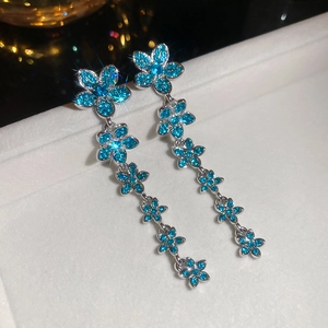 Macro detail of silver needle tassel earrings with blue zircon flower cascades