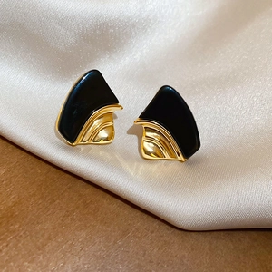 Detail of 18k gold plated geometric earrings with black resin inlay on beige silk