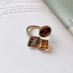 Macro detail of gold-plated open ring with zircon square and round brown stones