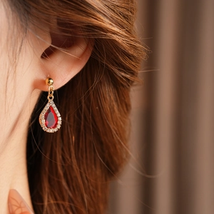 Detailed shot of waterdrop ruby earrings with sparkling crystals in gold plating