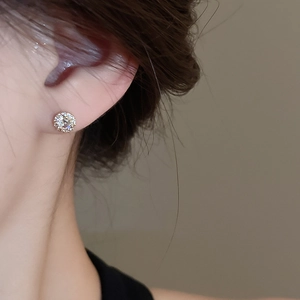 Macro view of gold-plated zircon stud earrings worn on a model for luxury detail