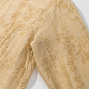 Detailed close-up of champagne jacquard fabric featuring floral embroidery and pleats