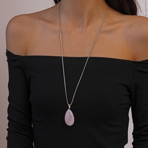 Close-up of a teardrop pink stone pendant on a silver chain worn on a model's neck