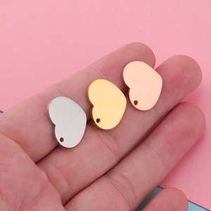 Detailed view of silver, gold, and rose gold heart pendants in hand with smooth mirror polish