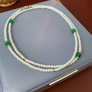 Close-up of double-layer faux pearl and green agate necklace on a velvet display box