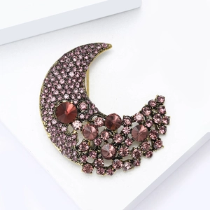 Detail of moon-shaped brooch with golden base and vibrant purple crystal rhinestones