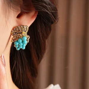 Vintage gold leaf and blue grape cluster earrings with rhinestones shown on model