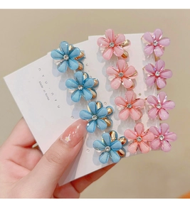 Close-up of frosted flower hair claws with rhinestones in blue, pink, and purple colors