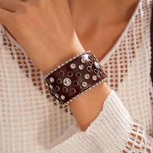 Gros plan d'un large bracelet punk en cuir marron avec cristaux et rivets métalliques