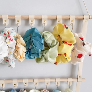 Hanging organizer detail showing colorful scrunchies on leather straps and wood rod
