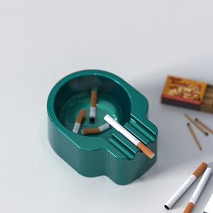 Detail of dark green skull-shaped resin ashtray mold showing cigarette slot and glossy finish