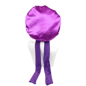 Macro shot of a purple satin hair bonnet showing smooth texture and long elastic straps