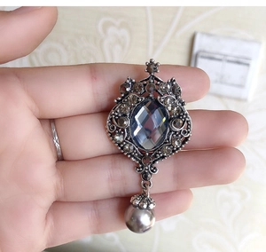 Macro view of vintage silver brooch with gray gemstone and pearl drop pendant