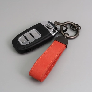Detail view of an orange suede leather keychain with gunmetal hardware and Audi car key