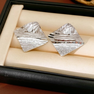 Detail view of silver square stud earrings with textured geometric facets in a gift box
