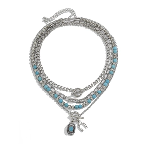 Detail of layered turquoise beaded necklace with lucky horseshoe pendant and OT buckle