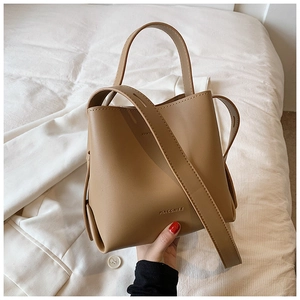 Detail showing camel PU leather bucket bag with top handle and embossed PIACCHEE logo