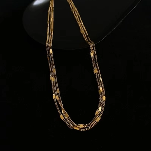 Close-up of triple-layered gold-plated necklace with polished metal sequins